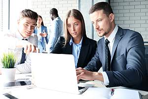 Business employees gathered around laptop