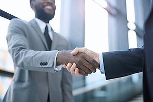 a certified public accountant shaking hands with a business owner after a financial reporting presentation