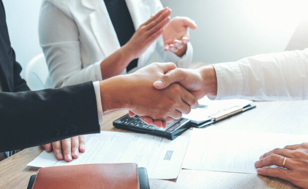 a government contractor shaking hands with a CPA after a successful government contract renewal