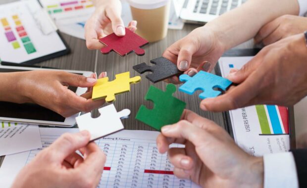 business owners holding puzzle pieces representing mergers and acquisitions
