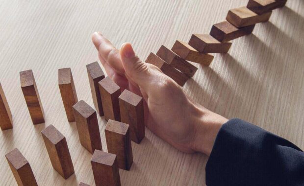 hand stopping the domino wooden effect risk management concept for business
