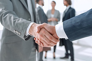 a professional CPA shaking hands with a government contractor after a successful REA