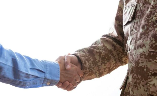military person and civilian shaking hands standing on white background