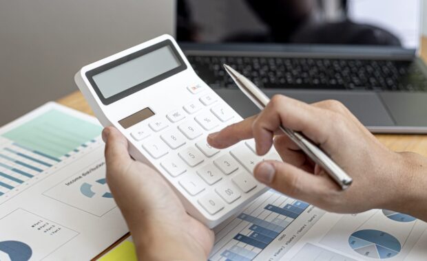 businessman using a calculator to calculate numbers on a company's financial documents