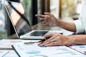 man on laptop and charts on table