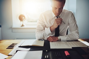 business man working on documents looking concentrated with briefcase and phone on the table