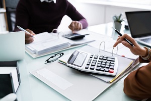 businesspeople calculating financial statement at desk