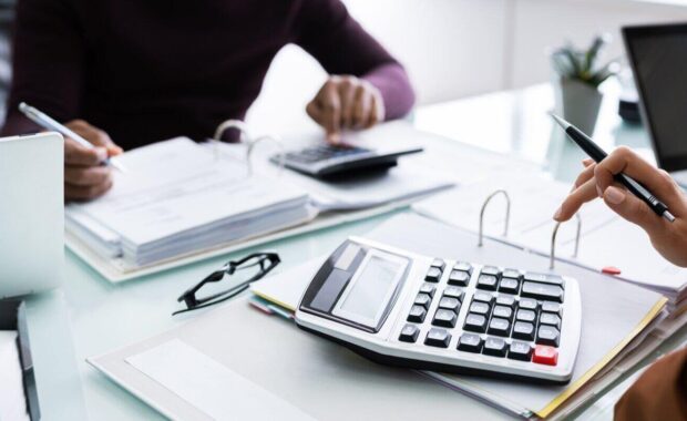 businesspeople calculating financial statement at desk