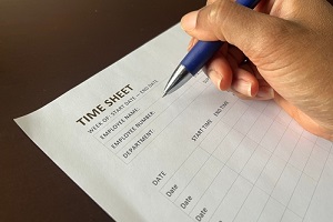 person holding a pen completing a time sheet