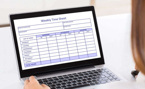 woman filling weekly time sheet on laptop in office