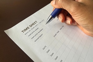 black person holding a pen completing a time sheet