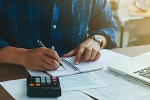 man analyzing data sheet with calculator