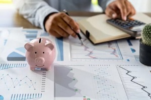 man reading graphs with piggy bank