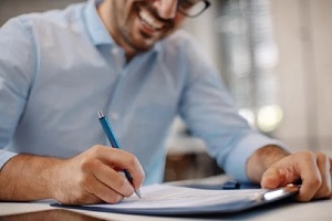 man signing contract and smiling