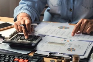 businesswoman working using calculator with money stack in office