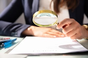 businesswoman looking at contract form through magnifying glass