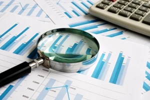 business papers with financial report and magnifying glass