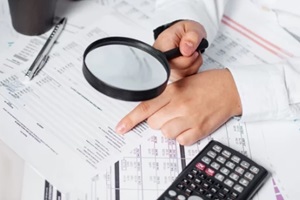 businessman using magnifying to review balance sheet annual