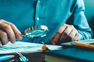 auditor checks the accounting records and reports with a magnifying glass