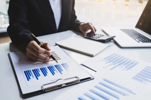 businessman analyzing investment charts with laptop and calculator