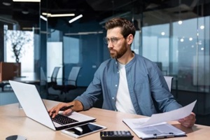 serious young man accountant, financier, analyst, auditor sits in the office at the table