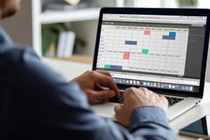 realistic image of individual utilizing laptop with editorial calendar