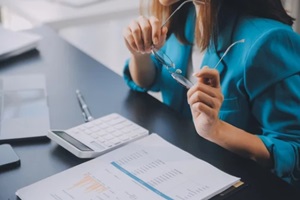 woman using calculator and laptop for doing math finance on an office desk, tax, report, accounting, statistics