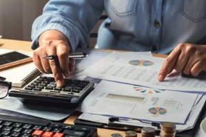 businesswoman working using calculator with money stack in office