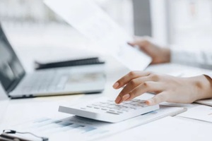 businessman using a calculator to calculate numbers on a company's financial documents