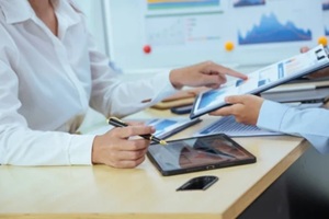 businesswomen sit at a table, engaged in a meeting