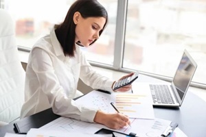 female accountant working on important documents with calculator in hand