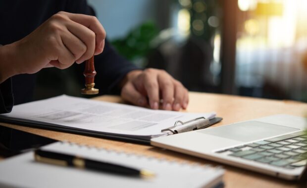 man stamping approval on financial, banking, or investment documents at his desk official paperwork