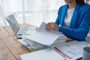 woman plans a finance and budget audit by reviewing organizing office financial documents