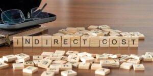 indirect cost word or concept represented by wooden letter tiles on a wooden table with glasses and a book