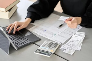 asian woman entering expenses into accounting software