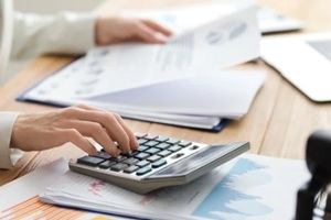 female accountant working with calculator and documents at table in office