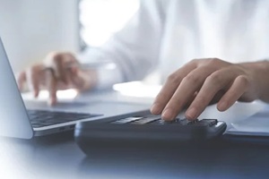 close up hands of accountant using calculator to calculate tax refund