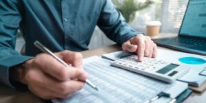 person using calculator and reviewing financial documents for accounting and budget planning