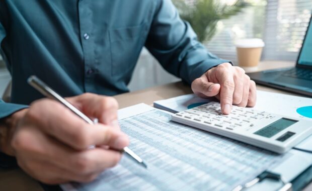 person using calculator and reviewing financial documents for accounting and budget planning