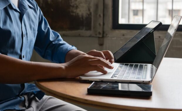 close-up image of a businessman typing on a laptop at his desk illustrates document management
