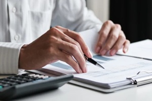 office administrator reviewing audit documents on table with calculator and financial file folders