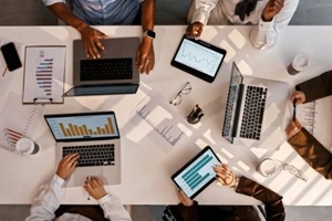 team working with graphs and data on laptops and tablets at office table