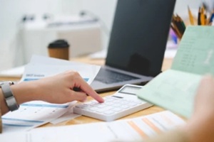 accountant or businesswoman checks the contents of his savings book in front of her laptop