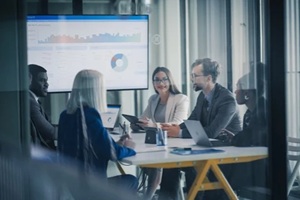 business team meets in a glass conference room to review dashboards