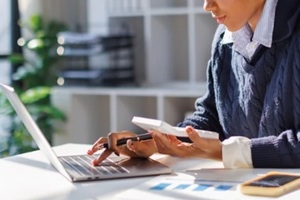 businesswoman using calculator to calculate and record company marketing data