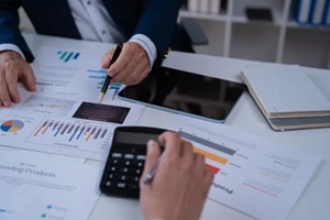 people are collaborating on financial analysis, using graphs and charts on paper documents to forecast trends and evaluate company performance