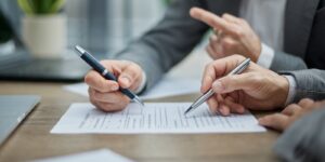 two professionals review documents at a wooden desk