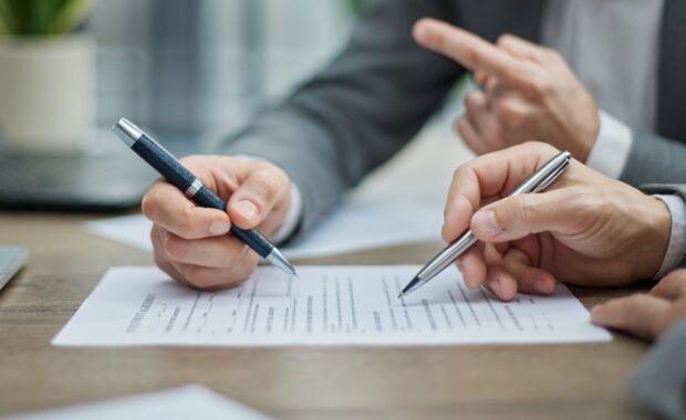 two professionals review documents at a wooden desk