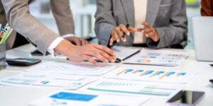 business team reviewing financial charts and reports at a desk during a planning meeting, with laptop, calculator, pens and smartphone