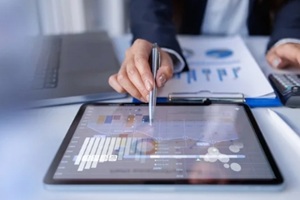 hand and graph on tablet laptop screen at desk accounting